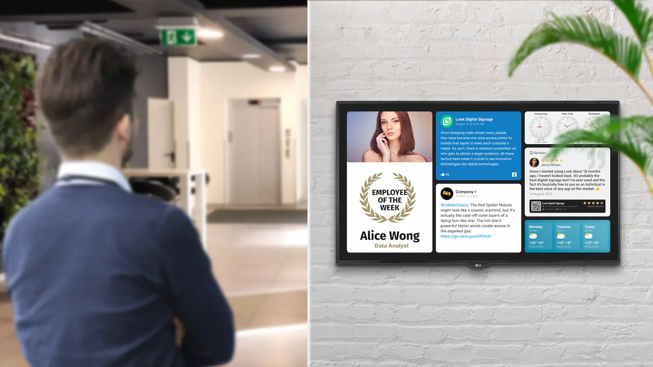 A wall-mounted screen in a hallway showing a notice board with a photo, news items and the weather